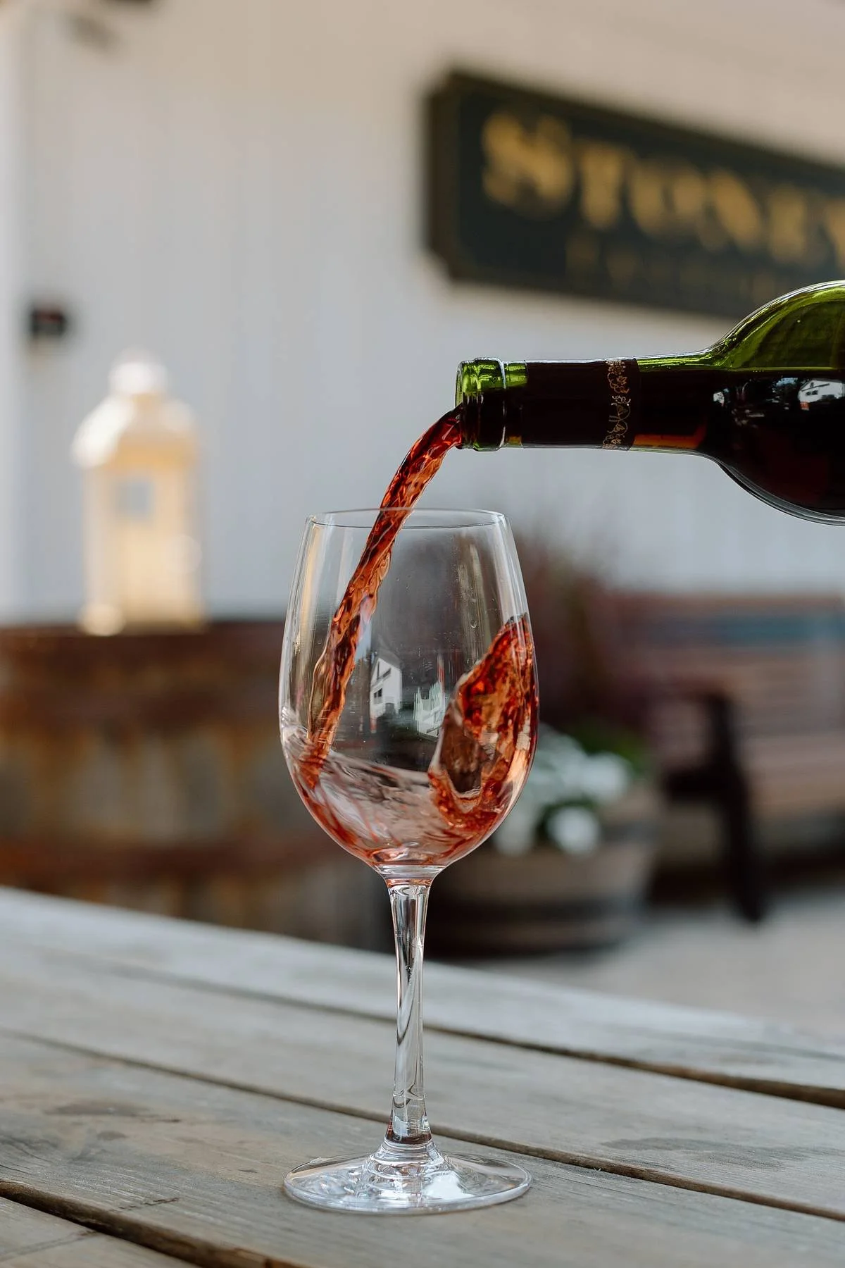 Red wine poured into a glass on a wooden table