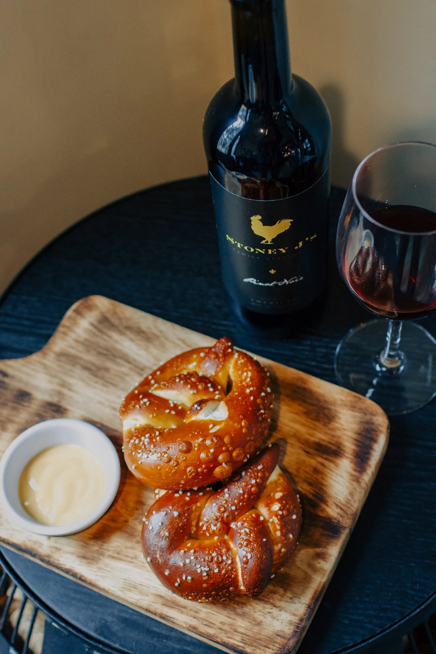A Bavarian pretzel with cheese dip and a glass of red wine