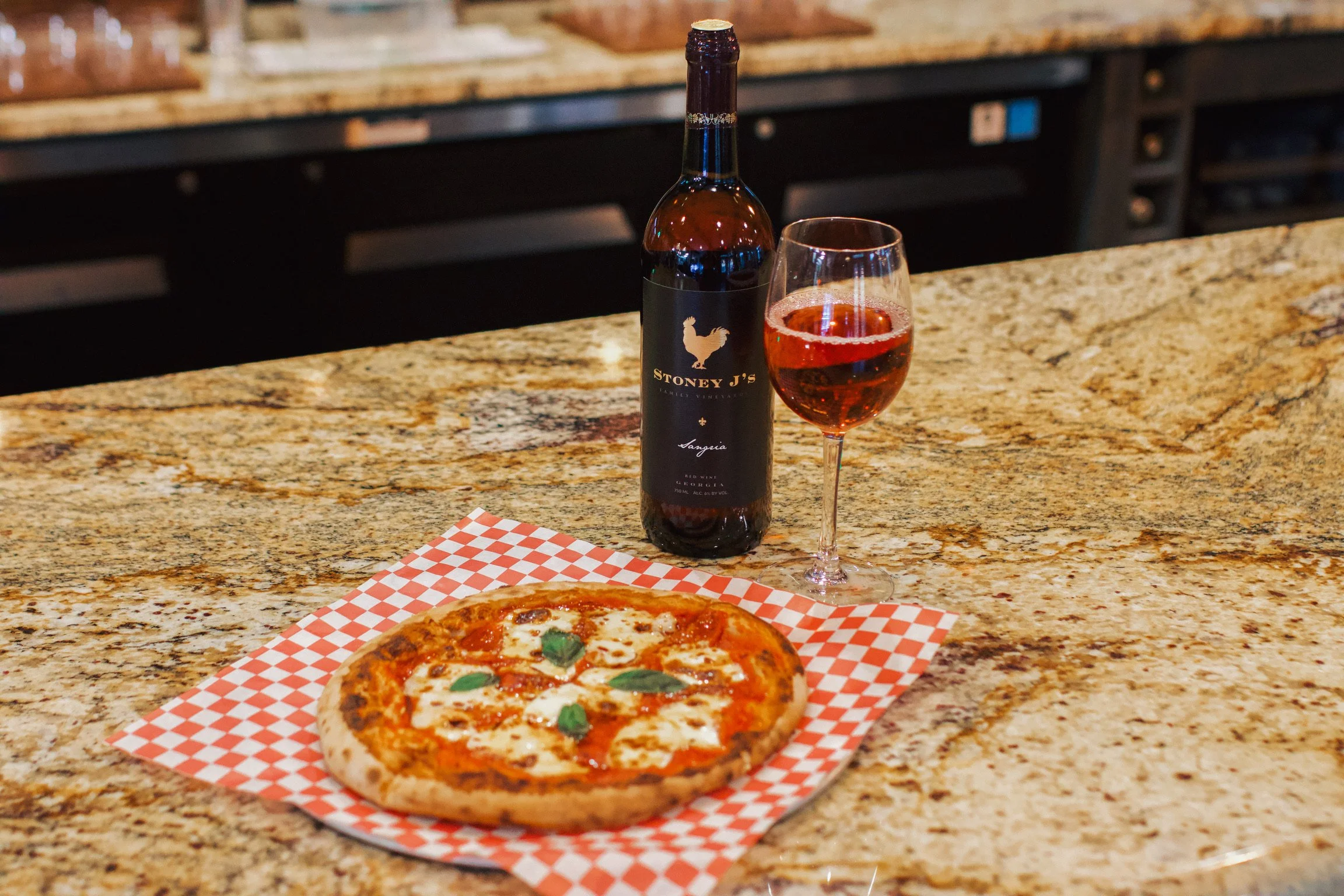 A margherita pizza beside a bottle of Stoney J’s wine