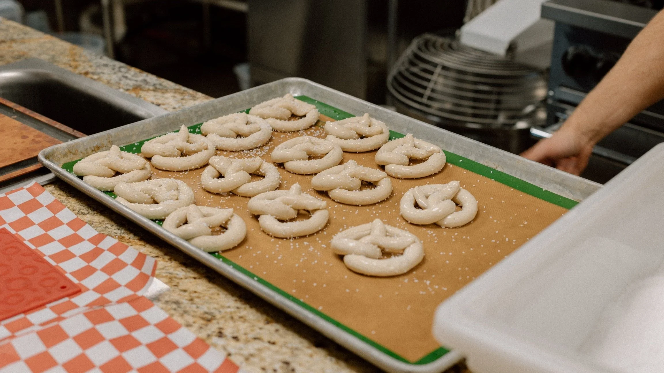 Pretzels shaped by hand on a sheet tray in the kitchen